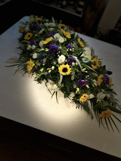Coffin Spray – Wildflower Style - A beautifully relaxed coffin spray arrangement, designed in a natural meadow style using a mix of fresh, seasonal flowers and textured foliage. This tribute features a vibrant blen