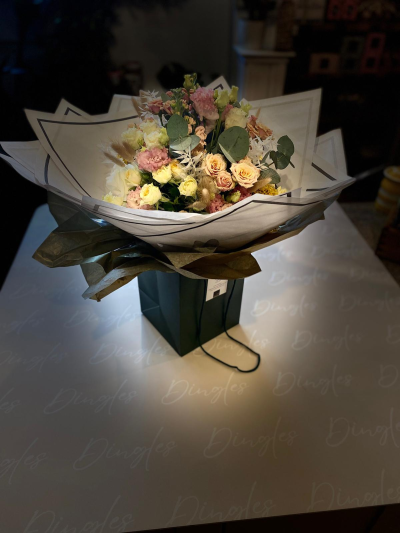 Pastel Hand-Tied Bouquet - A beautifully styled hand-tied bouquet, featuring a soft and elegant blend of fresh flowers in delicate pastel tones. This arrangement includes spray roses, carnations, seasonal blooms, and textured foliage, complemented by natural elements for added depth and interest.

Presented in premium layered wrapping and a stylish gift bag, this bouquet offers a modern and sophisticated alternative to traditional arrangements, making it perfect for effortless gifting.